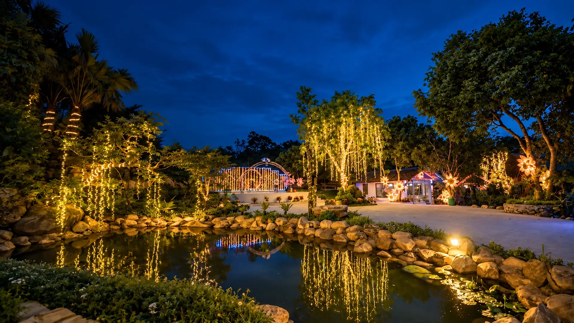 Vườn đèn lúc chạng vạng ở Sơn Thủy Retreat: dây đèn vàng rủ trên cây, soi bóng xuống hồ đá
