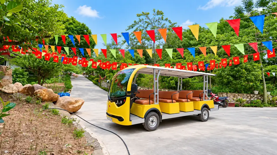 Xe điện vàng của Sơn Thủy Retreat chạy giữa đường trang trí cờ nhiều màu, dùng đưa khách đi tham quan quanh Thanh Thủy