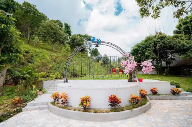 Sân khấu tròn ngoài trời với vòm sắt, cây hoa đào trang trí và bồn hoa
